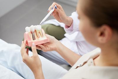 woman looking at dental implant diagram in beaverton