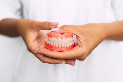 woman holding dentures | Beaverton OR Dentist