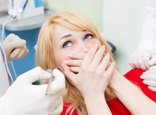 woman covering mouth in fear in exam chair | sedation dentistry beaverton