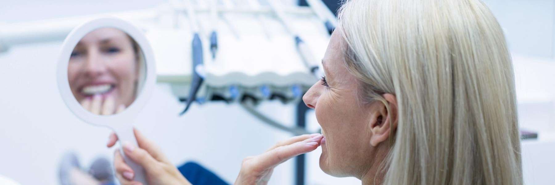 woman smiling in mirror | implant dentist beaverton